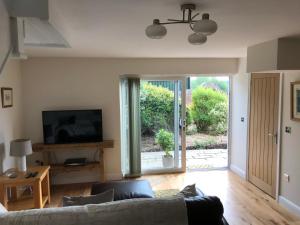 a living room with a couch and a sliding glass door at Wagtail Cottage in Tarporley