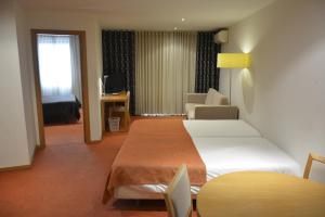 een hotelkamer met 2 bedden en een woonkamer bij Paredes Hotel Apartamento in Paredes