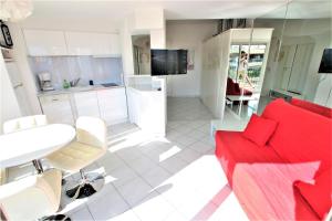 a living room with a red couch and a kitchen at Nice apartment last floor with terrace and clear view on the sea in Cannes