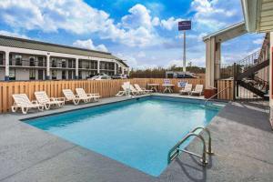 a swimming pool with lounge chairs and a hotel at Super 8 by Wyndham Florence in Florence