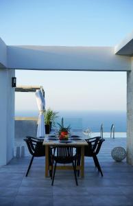 a table and chairs on a patio with a view at Eva Villas East, with infinity pool & and panoramic sea view in Gerani