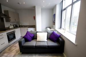 ein Wohnzimmer mit einem Sofa und lila Kissen in der Unterkunft StayZo - Executive City Centre Apartment 2 in Bradford