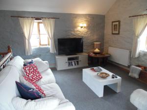a living room with a white couch and a tv at Brambles Cottage in Boyton
