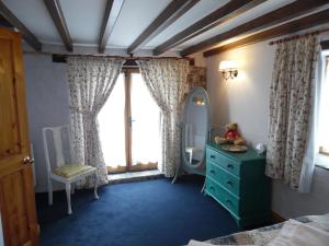a bedroom with a mirror and a blue dresser at Brambles Cottage in Boyton
