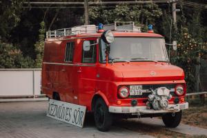 an old red fire truck parked in a parking lot at NOPARA gyógySERtár APARTMAN, sörfőzde, bisztró - Petőfi utca 29 in Tiszafüred