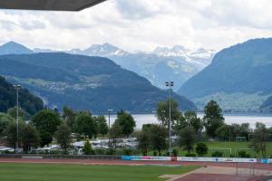 a view of a tennis court with mountains in the background at Anstatthotel Horw - self-check-in in Luzern