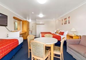a hotel room with two beds and a table and a couch at Econo Lodge Alabaster in Cowra