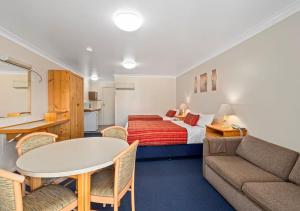 a hotel room with a bed and a couch and a table at Econo Lodge Alabaster in Cowra