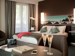 a hotel room with a bed and a table with wine glasses at Mercure Pont d’Avignon Centre in Avignon
