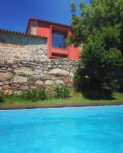 a house with a red window and a stone wall at Quinta Da Ribeira in Ponte de Lima