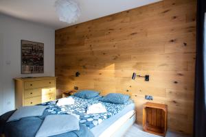 1 dormitorio con 1 cama y pared de madera en Apartament ZIELONA, en Krynica-Zdrój