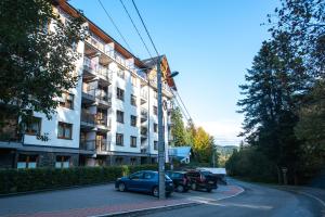 un coche aparcado en un aparcamiento al lado de un edificio en Apartament ZIELONA, en Krynica-Zdrój