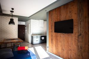 een woonkamer met een televisie aan een houten muur bij Apartament ZIELONA in Krynica Zdrój