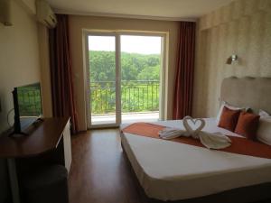 シネモレツにあるFamily Hotel Dayana Beachのベッドと大きな窓が備わるホテルルームです。