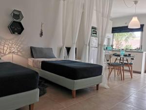 a bedroom with two beds and a table and a kitchen at Casa Mós in Lagos