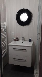a bathroom with a sink with a wreath on the wall at LE CHALET SUISSE - Chambre aux fleurs in Le Vicel