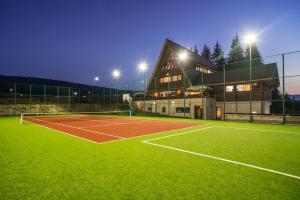 a tennis court in front of a building with lights at Pensiunea Smida Park in Smida