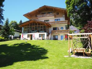 ein großes Haus auf einem grünen Rasen in der Unterkunft Pension Hofweyer in Ramsau am Dachstein