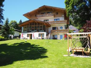 a large house on top of a green lawn at Pension Hofweyer in Ramsau am Dachstein