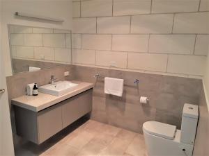W łazience znajduje się umywalka, toaleta i lustro. w obiekcie Port Central No 4 w mieście Port Campbell