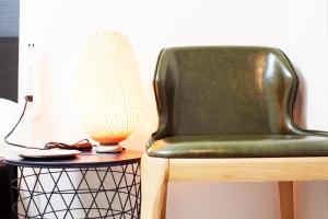 a green chair next to a side table with a lamp at Hotel Shu in Tokyo