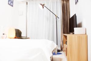 a bedroom with a bed and a lamp and a tv at Hotel Shu in Tokyo
