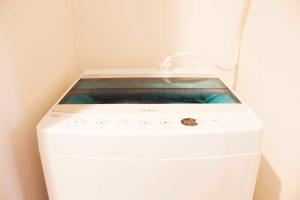 a white washing machine in a corner of a room at Hotel Shu in Tokyo