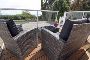 two wicker chairs and a table on a deck at Viewbank Cottage in Whiting Bay