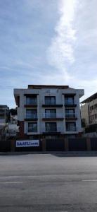a white apartment building with a sign in front of it at Saatlı Hotel in Çeşme