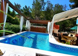 斯拉蒂納的住宿－Villa Kale Apartments，一个带遮阳伞的游泳池,旁边是一张桌子