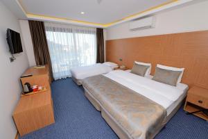 a hotel room with two beds and a television at Saatlı Hotel in Çeşme