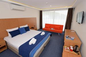 a hotel room with a bed and a chair at Saatlı Hotel in Çeşme