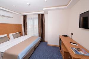 a hotel room with a bed and a flat screen tv at Saatlı Hotel in Çeşme