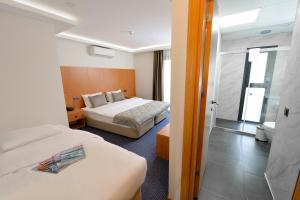 a hotel room with two beds and a bathroom at Saatlı Hotel in Çeşme