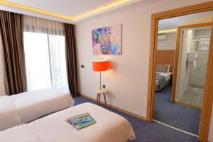a hotel room with two beds and a mirror at Saatlı Hotel in Çeşme
