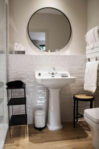 Baño blanco con lavabo y espejo en Les Manoirs des Portes de Deauville - Small Luxury Hotel Of The World en Deauville