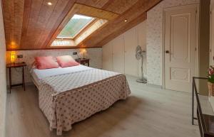 a bedroom with a bed with pink pillows and a window at Casa Manoli Luarca in Almuña