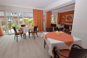 a restaurant with two tables and chairs and windows at Hotel-Pension Achtern Diek in Büsum
