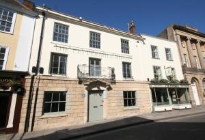 a white building with a balcony on a street at The Peppermill Town house Hotel & Restaurant in Devizes