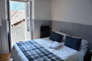 uma cama com almofadas azuis num quarto com uma janela em Rocks apartment Colonno em Colonno
