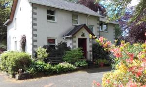 una casa blanca con una puerta roja y algunas flores en Grovewood House Retreat en Kirkbean