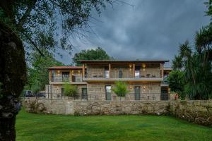 a large house on a stone wall with a yard at Casa do Rio in Mondim de Basto