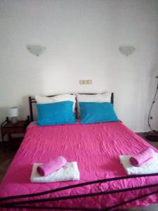 a bedroom with a pink bed with two towels on it at Nikos Rooms in Loutra Edipsou