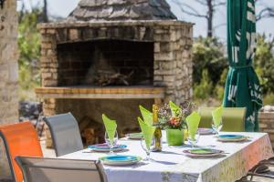 a table with plates and wine glasses and a fireplace at House Vesna Kupinova in Milna