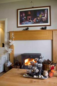 a living room with a fireplace and a table with a fire place at Airlie House Self Catering in Strathyre