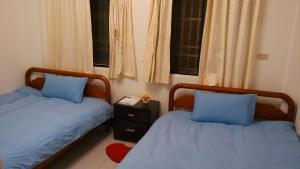 two beds with blue pillows in a bedroom at Love Hualien Hostel in Hualien City