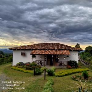 mały biały dom z dachem krytym strzechą w obiekcie Hacienda Cafetera La Gaviota w mieście Chinchiná