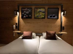 hotel des Sapins في Lanarce: سريرين في غرفة بها لوحات على الحائط
