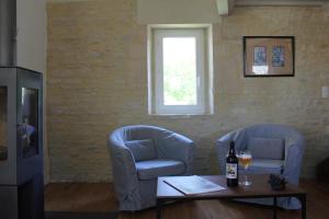 a living room with two chairs and a table with a bottle of wine at Cottage d'Exception - Coeur de Normandie 