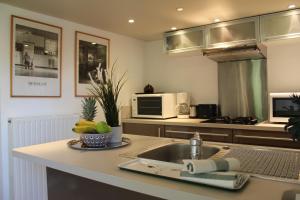 a kitchen with a sink and a laptop on a counter at Cottage d'Exception - Coeur de Normandie in Vienne-en-Bessin